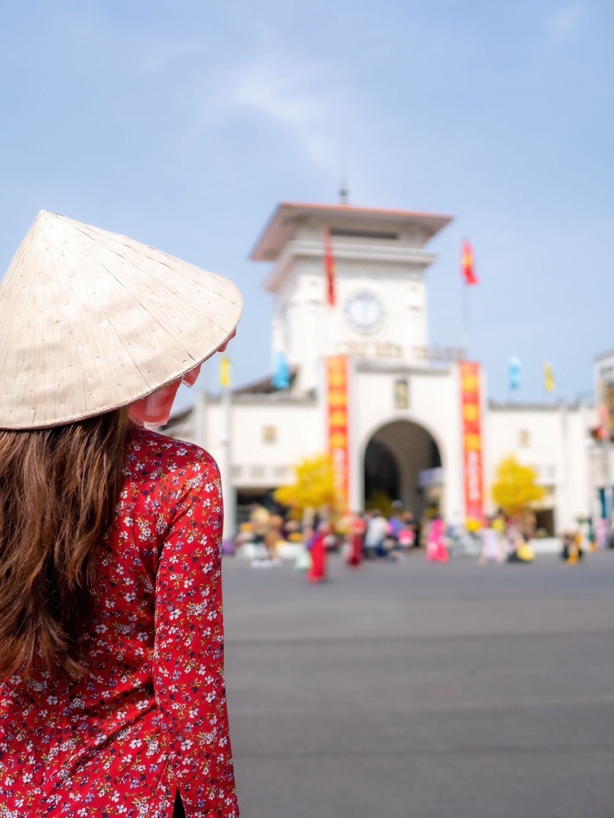 Cô gái Việt Nam trong tà áo dài đi dạo trước chợ Bến Thành, thành phố Hồ Chí Minh, Việt Nam 1200 x 1600px